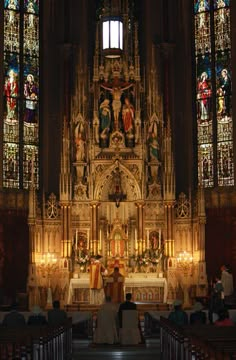 the bride and groom are sitting at the alter in front of the stained glass windows