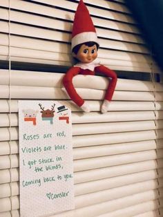 an elf is hanging on the window sill next to a sign that says roses are red violets are blue i got stuck in the blinds, coming back in