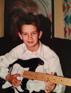 a young boy is holding an electric guitar