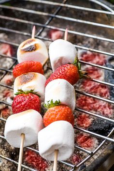 strawberries and marshmallows are being grilled on the grill