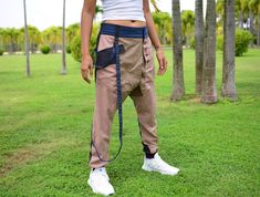 a woman standing in the grass with her back to the camera, holding a leash