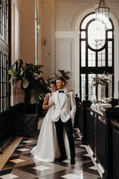 a bride and groom are standing together in an elegant hall with black and white checkered flooring