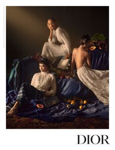 three women sitting on top of a bed next to each other in front of a dark background