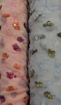 two pillows with different colored sequins and beads on them sitting next to each other