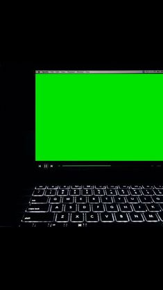 a laptop computer with a green screen on it's keyboard, lit up in the dark