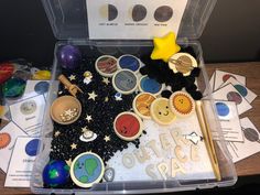 a plastic container filled with lots of different types of buttons and magnets on top of a wooden table