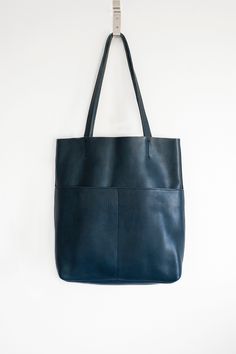 Natural-grained leather unlined tote bag. It features two open exterior pockets and one internal zippered pocket. It comes with fixed leather handles. It’s held shut by a sturdy snap closure. Textured Leather Tote Satchel For On-the-go, Blue Textured Leather Satchel For Everyday Use, On-the-go Textured Leather Tote Bucket Bag, Blue Textured Leather Everyday Shoulder Bag, Blue Textured Leather Shoulder Bag For Everyday, Blue Everyday Shoulder Bag With Textured Leather, Classic Workwear Bags With Flat Pocket, Blue Textured Leather Tote Shoulder Bag, Blue Textured Leather Tote Bag