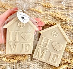 two cookies shaped like houses with the words home and heart on them are being held by someone's hand