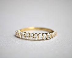 a yellow gold wedding band with five round cut diamonds on the side, sitting on a white surface