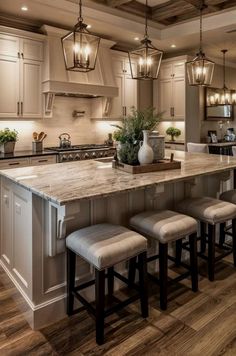 a kitchen island with four stools in front of it and lights hanging from the ceiling