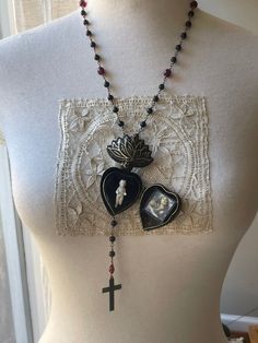 Handmade, each 6mm matte black onyx bead and blood red glass bead garnet has been hand wrapped with brass wire. doll is antique, from the late 1800s and excavated from a old German factory (will be a similar doll)! The sacred heart locket is patinated (unknown date). The bottom chain has been soldered to the back of the heart.  Brass blackened Crucifix is antique from Lourdes, France.  Well-made, for light use or decor.  MADE TO ORDER, meant to look IMPERFECT,  Custom orders welcome & will be extra $.   Other meerschaum repro pendants NOT included. Charlotte Necklace, Wire Doll, Antique Rosary, Lourdes France, French Brocante, Frozen Charlotte, Onyx Bead, Heart Locket