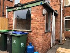 a brick building with two green trash cans and a blue fire hydrant next to it