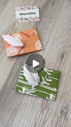 two envelopes are sitting on the floor next to each other and one has an origami bird