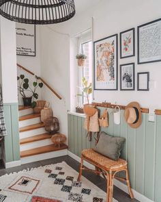 a room with some pictures on the wall and a chair in front of it next to a stair case