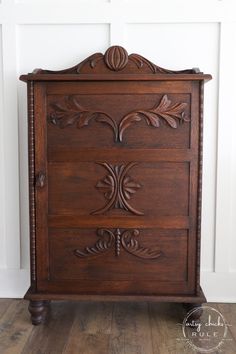 an old wooden cabinet with carvings on the front and sides, sitting against a white wall