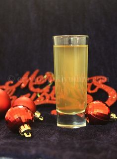 a glass filled with liquid sitting on top of a table next to christmas ornaments and decorations