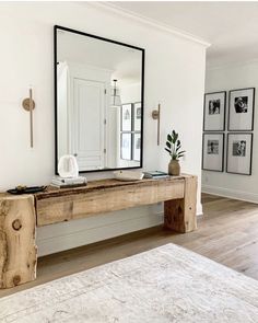 a large mirror sitting on top of a wooden table next to a white rug in a living room