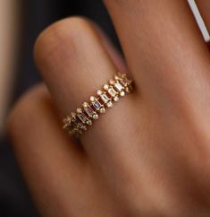 a woman's hand with a gold ring and diamond band on her left wrist