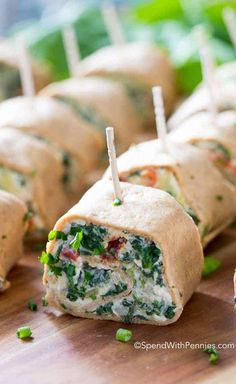 spinach and cheese roll ups with toothpicks on a cutting board, ready to be eaten