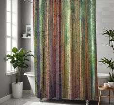 a bathroom with a shower curtain that has trees painted on it and is next to a bathtub