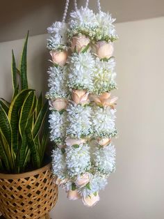 a flower arrangement hanging from a wall next to a potted plant