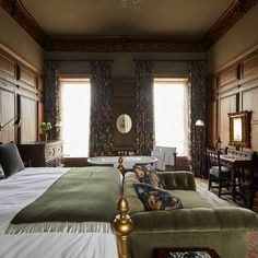 a large bed sitting inside of a bedroom next to two windows