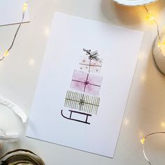 a card with a present on it sitting next to some christmas lights and other decorations