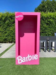 a pink box with the word barbie on it in front of a table and chairs