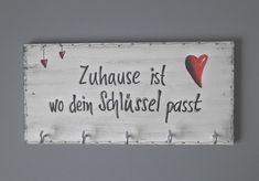 a wooden sign with hearts hanging from it's sides that says, zuhausse ist wo dei schlussel passe