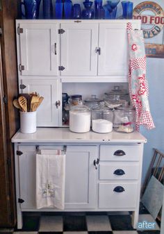 an old fashioned kitchen with white cupboards and blue glassware on the top shelf