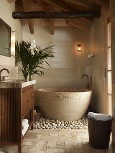 a large bath tub sitting next to a sink in a bathroom under a wooden ceiling