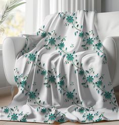 a white couch covered in a blanket with green flowers on it