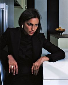 a woman sitting at a table with her hands on her knees and looking off to the side