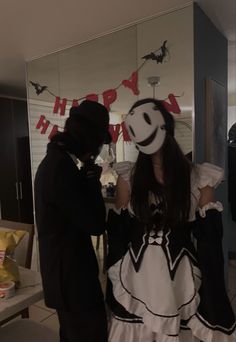 a man and woman dressed up in costumes standing next to each other, with the words happy halloween hanging above them