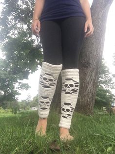 a woman standing in front of a tree wearing leg warmers with crochet