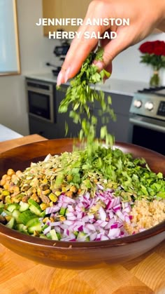 someone is sprinkling herbs into a salad in a bowl