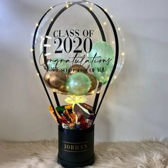 a glass vase filled with lots of different types of candies and balloons in front of a white wall