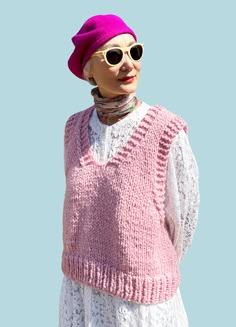 an older woman wearing sunglasses and a pink knitted sweater stands in front of a blue sky