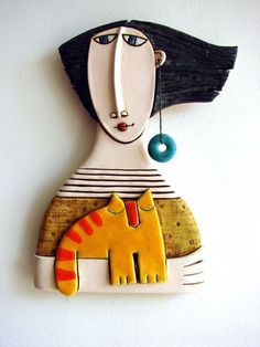 a ceramic wall hanging with a cat and a woman's face