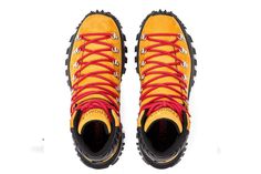 a pair of yellow hiking boots with red laces on the outstretches