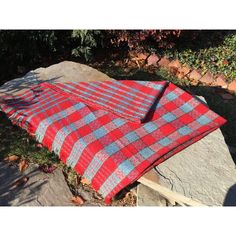 a red and blue blanket sitting on top of a rock