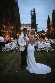 a man and woman standing next to each other in front of an outdoor dinner table