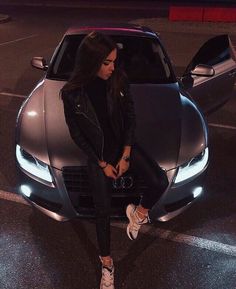 a woman sitting on the hood of a sports car