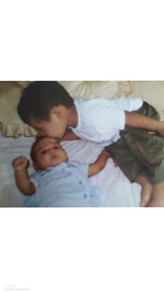 a young boy laying on top of a bed next to a little baby in his arms