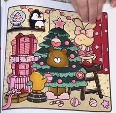 someone is holding an open book with a christmas tree and other items on it in their hands