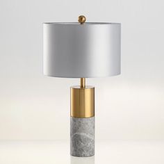 a table lamp with a marble base and gold trim around the top, sitting on a white surface