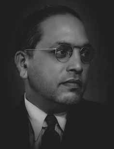 black and white photograph of a man with glasses looking off to the side, wearing a suit and tie