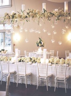 an image of a wedding reception setup with white flowers and chandeliers hanging from the ceiling