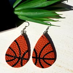 an orange and black basketball earrings sitting on top of a white table next to a plant