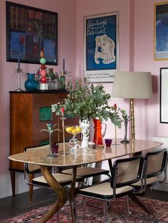 a dining room with pink walls and pictures on the wall